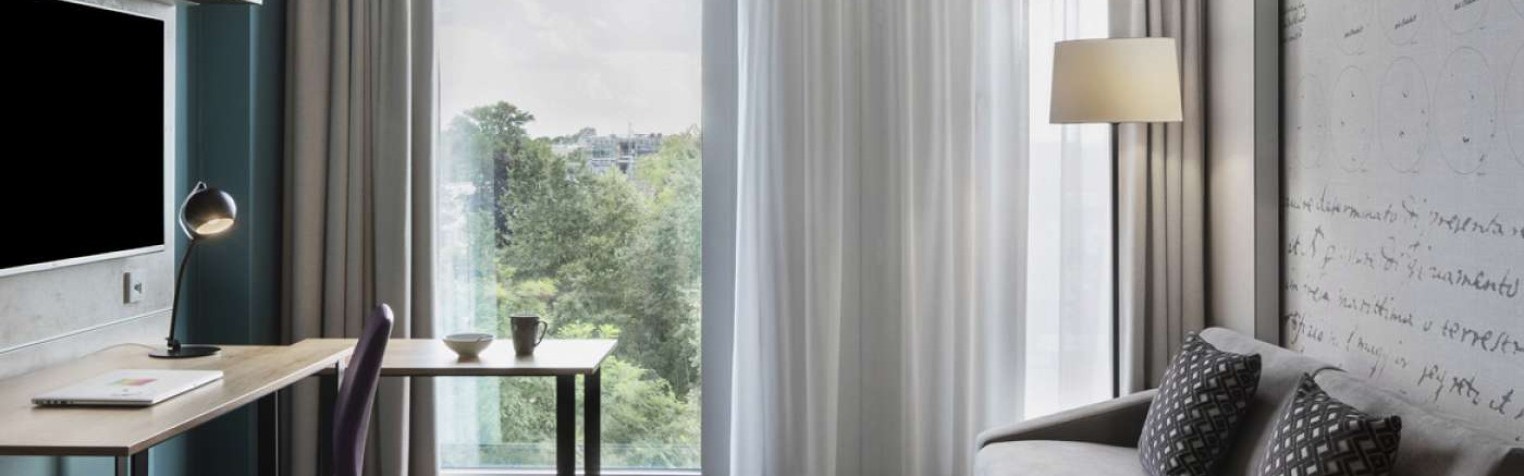 Zimmer mit großem Fenster und Einem Schreibtisch mit Sofa