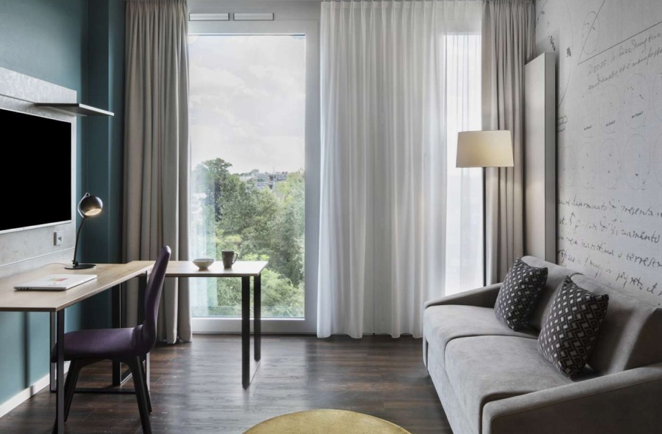 Zimmer mit Fenster, Sofa und Schreibtisch